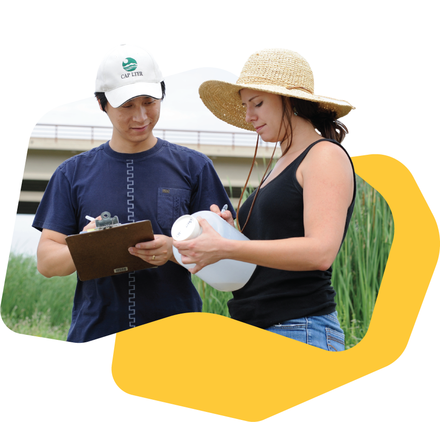 Two researchers outdoors recording field data, one holding a container and the other writing on a clipboard.